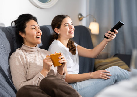 Two women relaxing at home watching TV