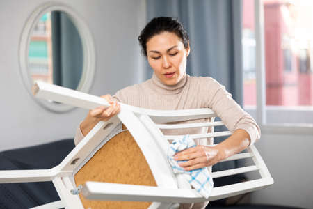 Woman washing chair during cleanupの写真素材