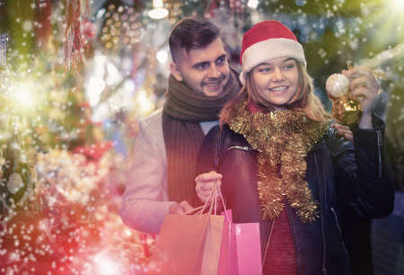 Joyful couple in Christmas hat with Christmas toys at fairの写真素材