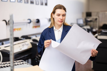 Woman checking large format paper after printing
