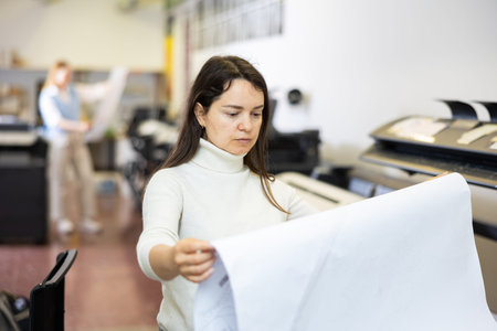 Woman checking large format paper after printing