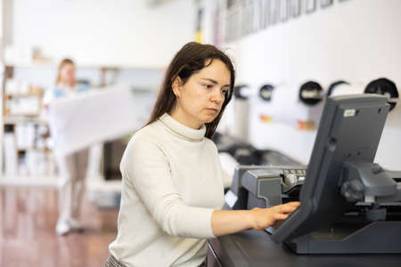 Woman using printer while working in print shopの写真素材