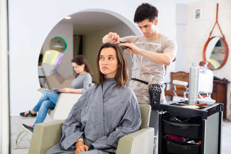 Young man hairdresser working with female clientの写真素材
