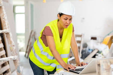 Female architect using laptop during repair worksの写真素材