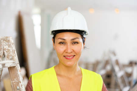 Portrait of positive woman builder during repair worksの写真素材