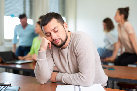 Tired man fell asleep at a lecture in university auditorium
