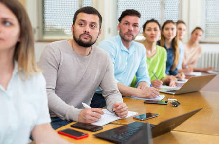 Adult students listening task for exam in classroomの写真素材