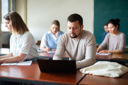 Bearded man university student sitting at table and using laptopの写真素材