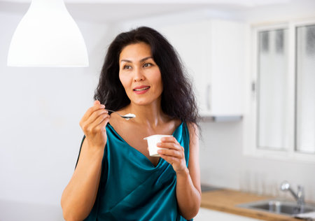 Portrait of woman eating yoghurt at home