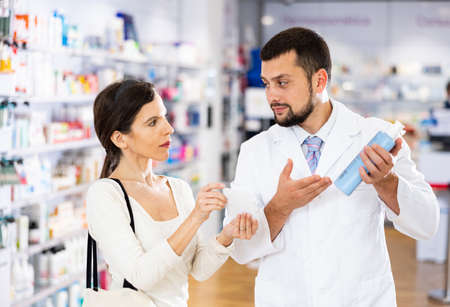 Pharmacist consulting woman buyer about hair care productの写真素材