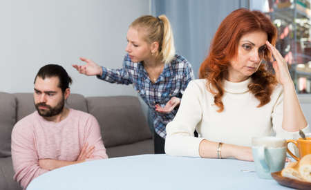 Mature woman sitting, man and girl having conflict on backgroundの写真素材