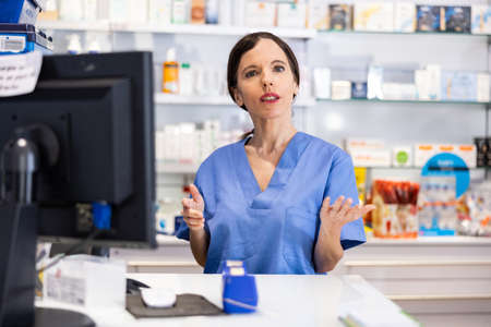 Female pharmacist standing behind counter in drugstoreの写真素材