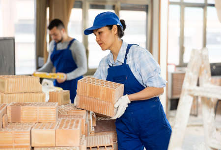 Repairman carrying bricks in construction siteの写真素材