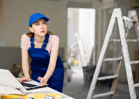 Portrait of a female builder who checks the work done using laptop