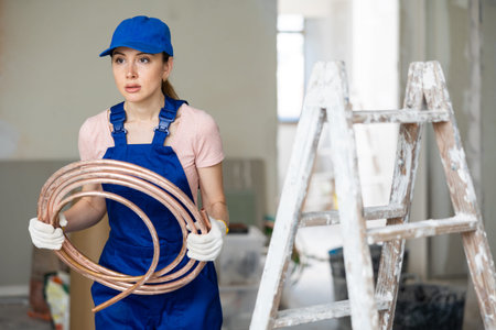 Female builder carrying conduit at renovating object