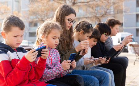 Children addicted in their phones outdoorsの写真素材