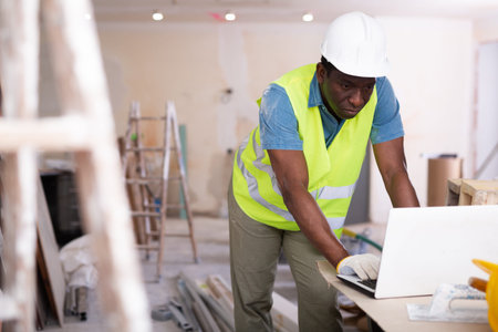 African american engineer checks a home renovation plan on a laptop