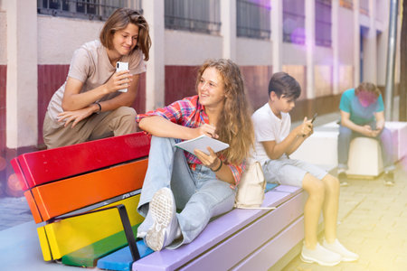 Teens of different ages talking and sitting on bench