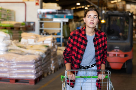 Woman carrying trolley or cart in storage warehouse
