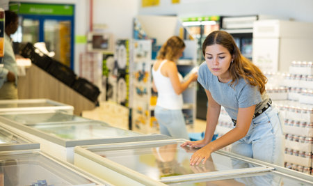 Young woman choosing frozen food in supermarket