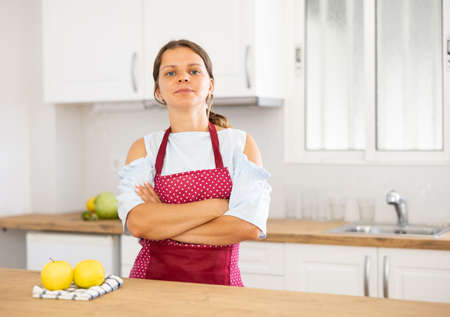 Young woman in apron posing in kitchenの写真素材
