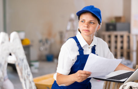 Portrait of a female builder who checks the work done using laptop