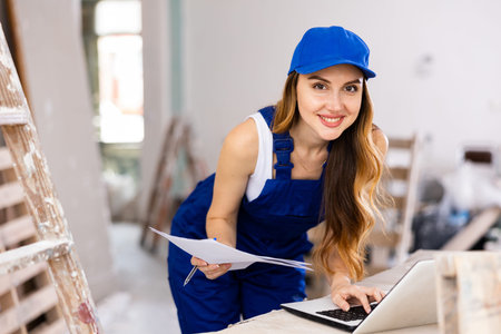 Sexy woman in uniform checks the house repair plan on a laptop