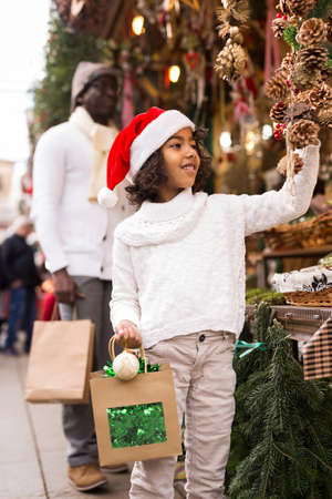 Girl with toy in hand choosing decorations at Christmas marketの写真素材