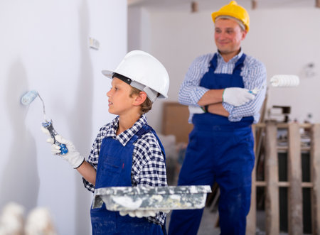 Boy painting wall, renovating home with fatherの写真素材