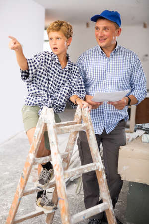 Man showing son blueprints in new homeの写真素材