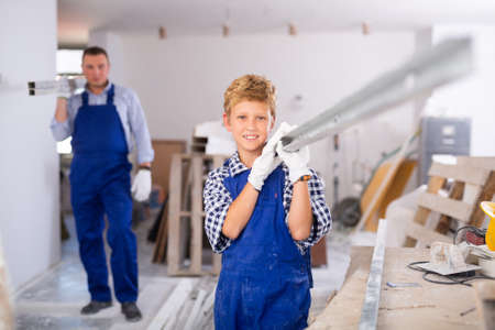 Preteen boy with father carrying building materialsの写真素材
