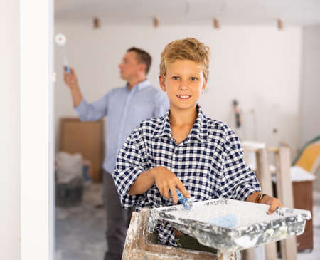 Portrait of positive young boy with paint rollerの写真素材