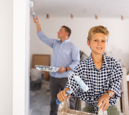 Portrait of positive boy with paint roller. Concept of helping parents to repair apartmentの写真素材