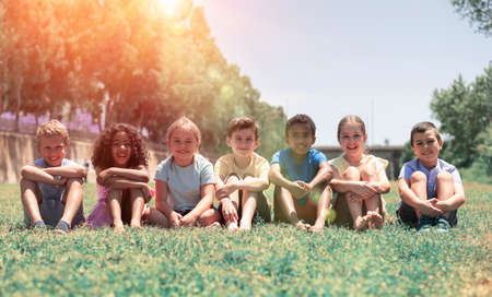 Happy team of friends children resting on grass at sunny dayの写真素材