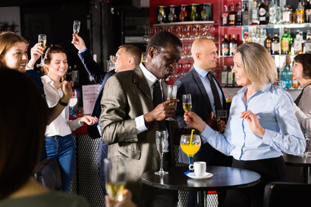 Cheerful African businessman having fun with mature female coworker during office party at nightclub