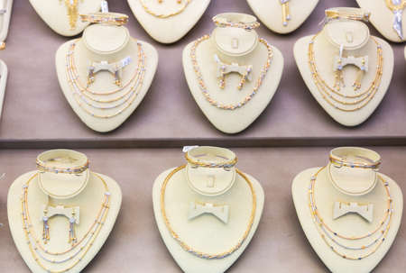 Gold jewelry at showcase of jewelry shop. Gold items in shop windows closeupの写真素材