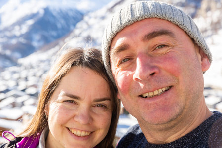 Cheerful man and woman making selfie during travel in Swiss Alps in winter