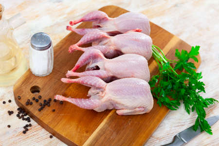 Raw gutted quails and condiments prepared for cooking on wooden tableの写真素材