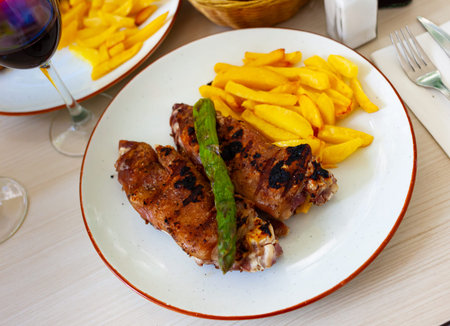 traditional spanish fried pettitoe with fries served on black plate on wooden table