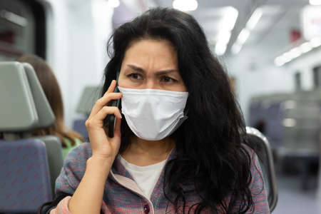 Woman traveler in a protective mask talking on a mobile phone in subway carの写真素材