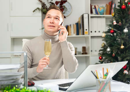 Cheerful office worker talking on phone, celebrating Christmas in officeの写真素材
