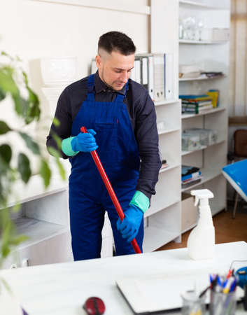 Male professional janitor dusting in office interiorの写真素材