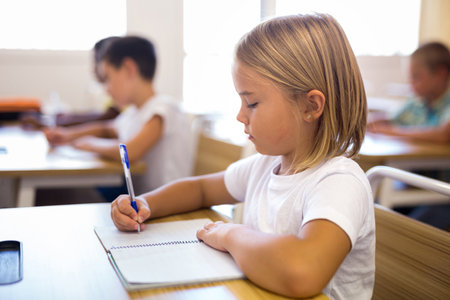 Young girl is sitting at the desk in classroom elementary schoolの写真素材
