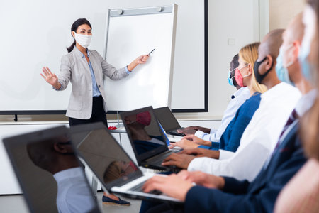 Asian woman business coach in protective mask lecturing to businesspeopleの写真素材