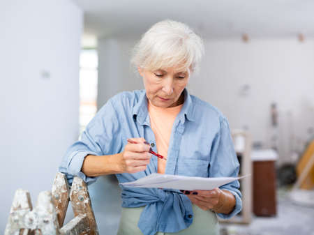 Mature woman making notes at renovating houseの写真素材