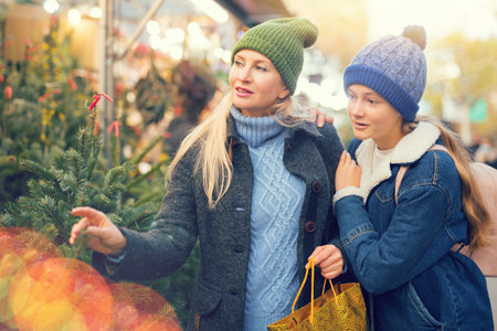 Girl and her mother purchasing christmas tree at marketの写真素材