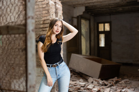 Young woman in jeans and black tee shirt posing in ruined buildingの写真素材