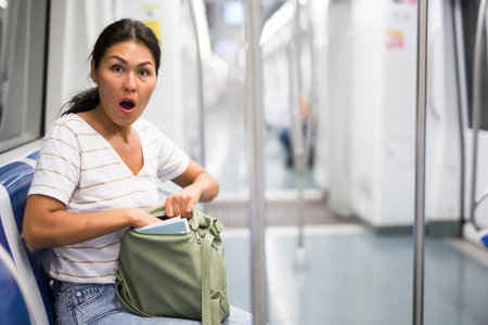 Oriental woman amazed by theft from her bag in subway carの写真素材