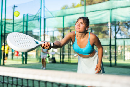 Fit young woman playing padel tennis on open courtの写真素材