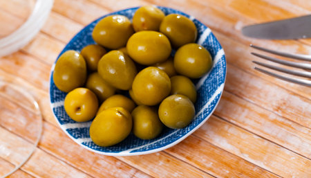 Pickled green olives in bowl on tableの写真素材